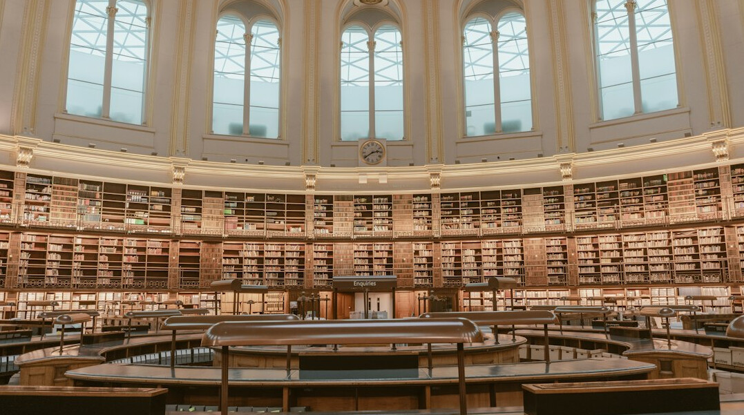Historic library reading room with tall bookshelves and warm light